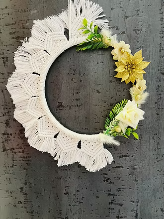 Handwoven white cotton macramé wreath with gold floral accent, ivory roses, and greenery, boho wall decor