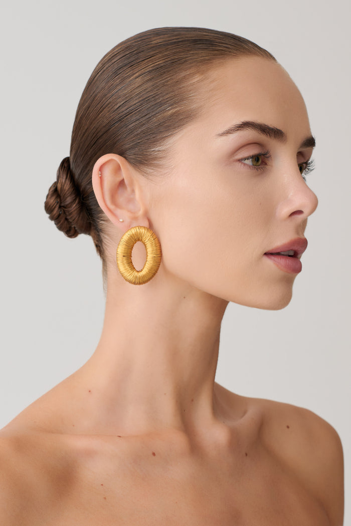 Woman wearing round gold studded earrings.